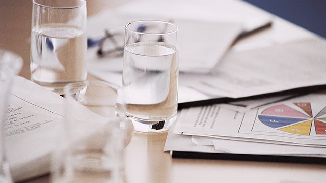 A table with glasses of water and paper with graphs on them.