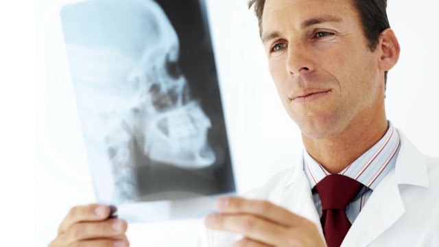 A doctor looking at an X-ray of a skull.