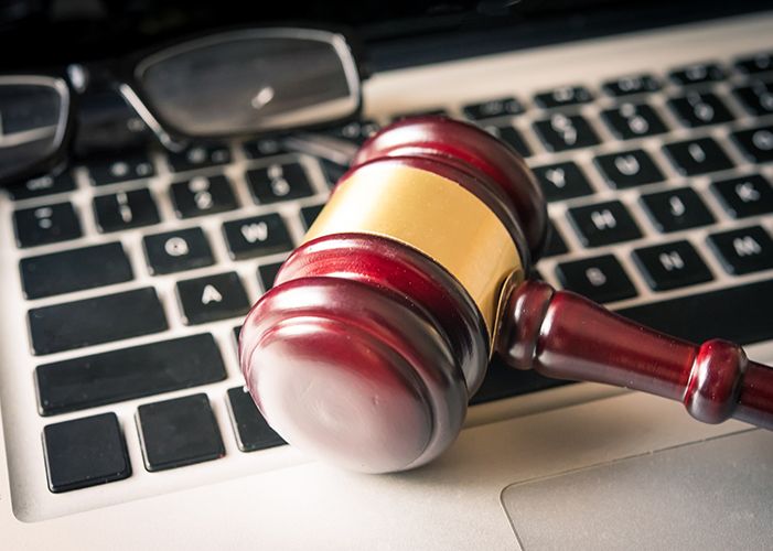 A computer keyboard with eye glasses and a judge's gavel sitting on top of it.