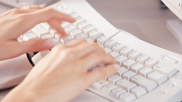 A pair of hands typing on a keyboard.