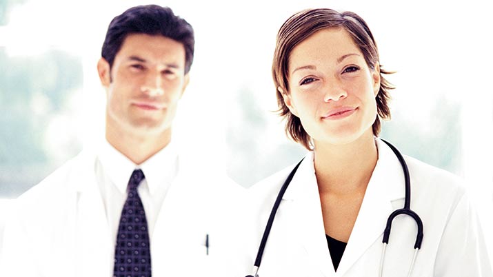Two medical professionals, one man with a white coat and a black tie and a woman with a white coat and stethoscope around her neck to represent six sigma's impact on the healthcare industry.