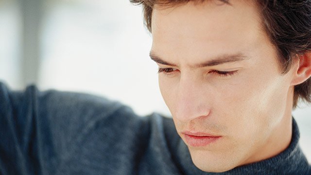 A man in a charcoal colored turtleneck sweater looking away from the camera.