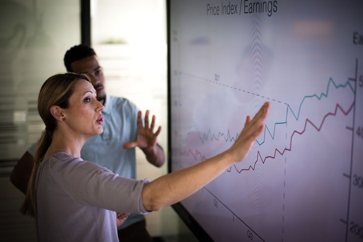 A businesswoman giving a presentation on data analysis and potential cost benefits.