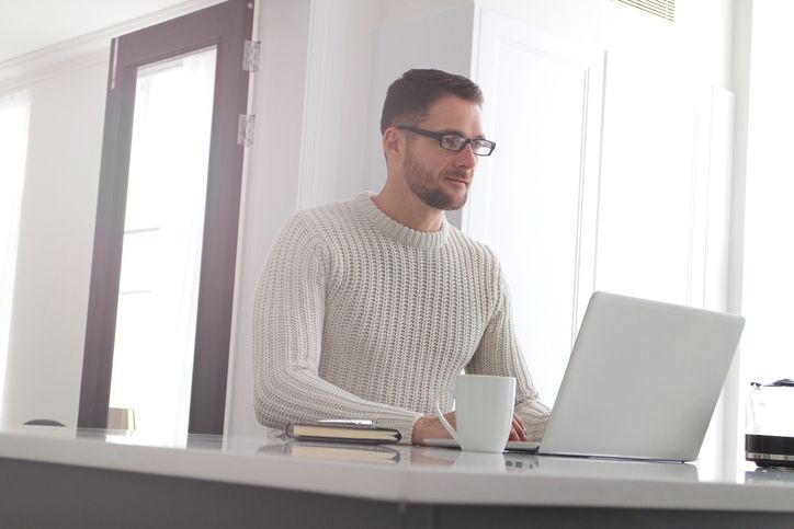 An adult professional works on his laptop at home.