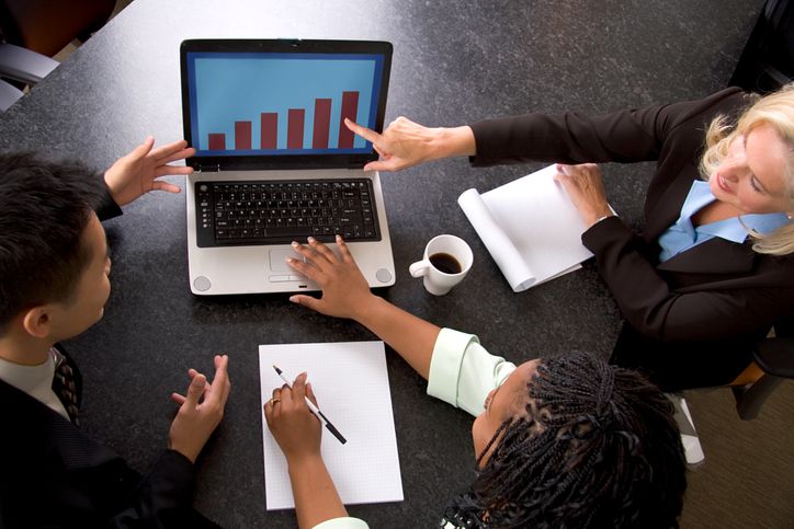 A business team looks at business growth on a computer.