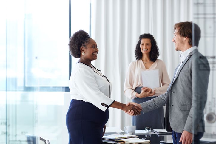 A hiring manager shakes the hand of a new employee.