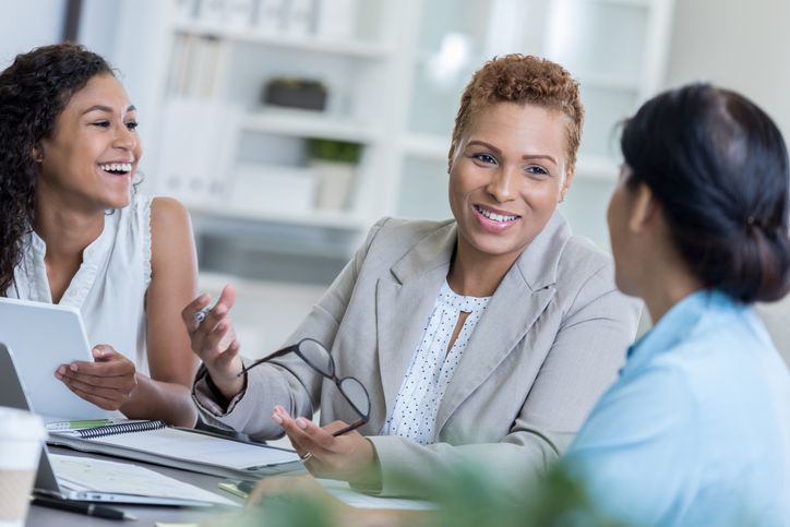 Organizational Leadership depicted as businesswoman discusses a project with her team.