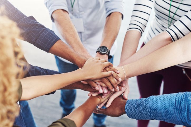 Closeup shot of a group of people joining hands in a huddle