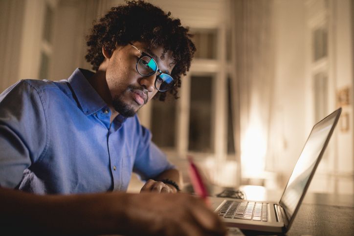 Professional studying on computer taking notes.