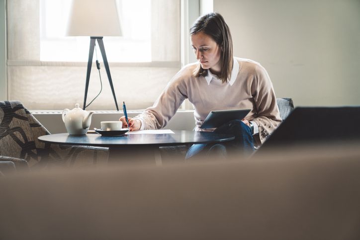 Woman sitting an home on laptop writing notes