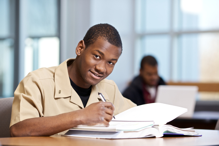 Military student in beige uniform smiling while studying