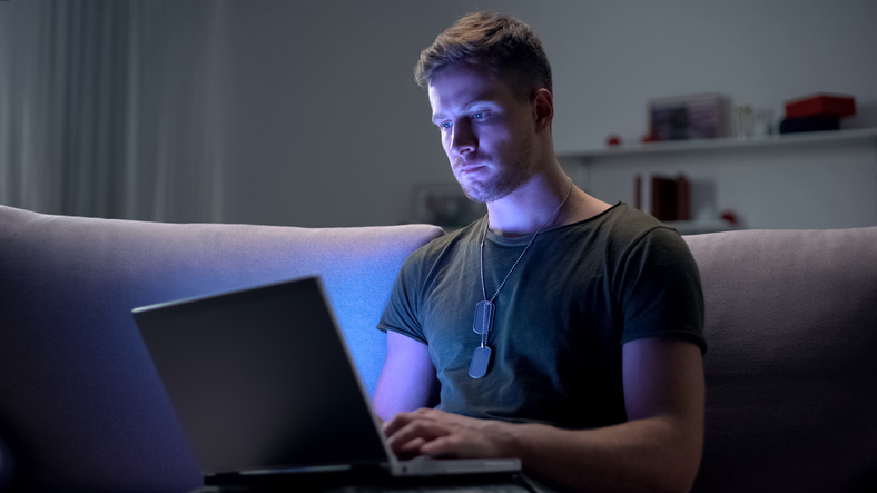 Military servicemember using laptop at home